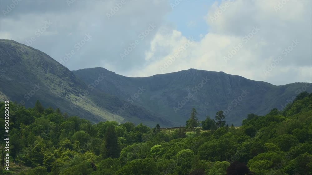 Clouds blowing from behind mountains as patches of sunlight race over mountains and trees. Time lapse. Lake District, Cumbria, UK Clouds blowing from behind mountains as patches of sunlight race over mountains and trees. Time lapse. Lake District, Cumbria, UK