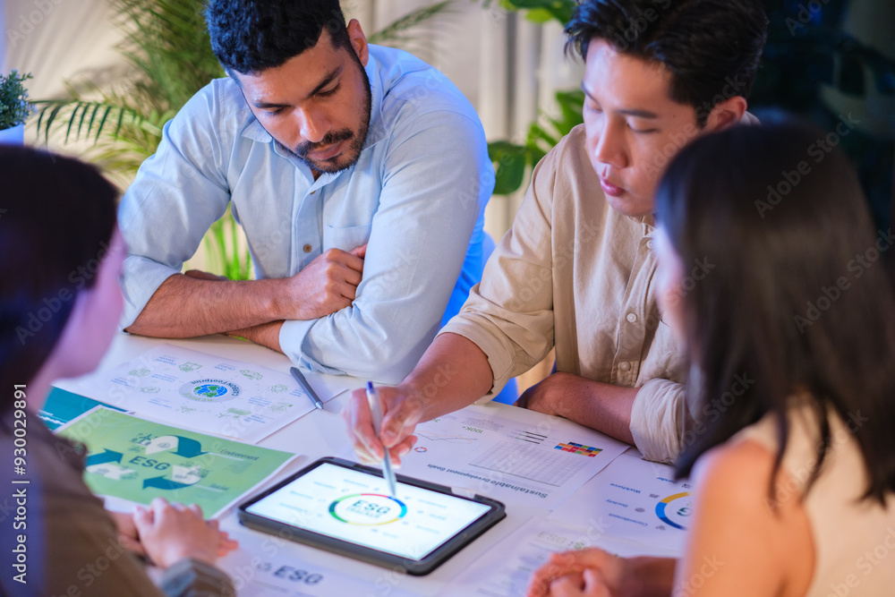 diversity team brainstorming focused on ESG (environment,social,governance) with tablet or sdgs goals in a sustainable green office at night diversity team brainstorming focused on ESG (environment,social,governance) with tablet or sdgs goals in a sustainable green office at night