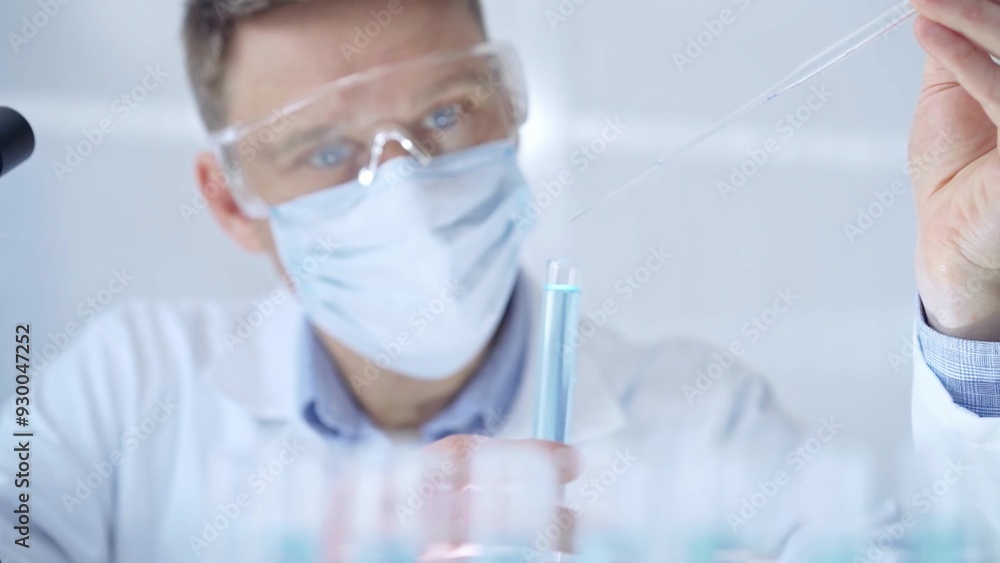 Man with safety glasses and blue mask is working with lab tubes Man with safety glasses and blue mask is working with lab tubes