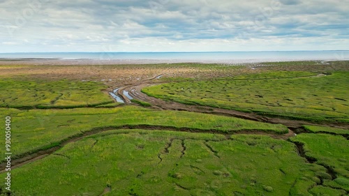 Cracked mud flats in a salt marsh. Aerial: Tidal mudflats, Abstract textures in a cracked coastline, Salt marshes at low tide exposing mud flats and streams at Freiston Shore Lincolnshire UK photo