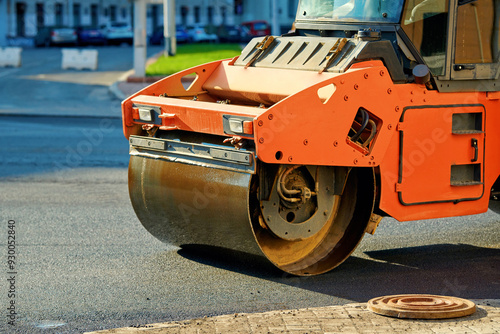 Vibratory roller compactor paving road in the city, road repair work. Laying new asphalt pavement. Asphalt paving machine and vibrating roller drum compactor, city road resurfacing