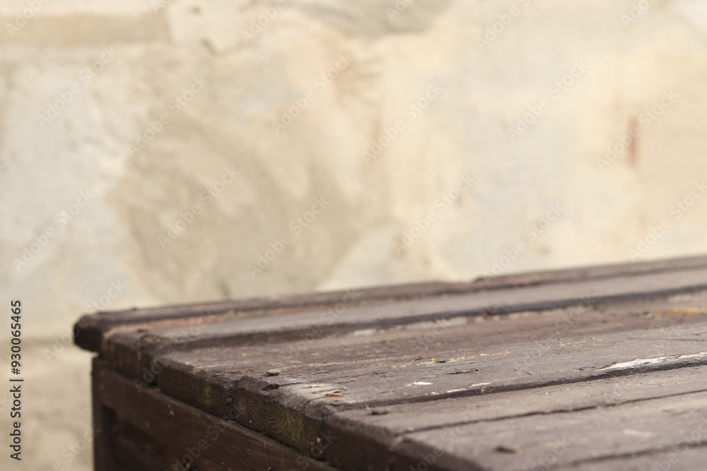 Wooden plank table with blurred concrete wall background, selective focus. Empty old table and wall for product display or installation
