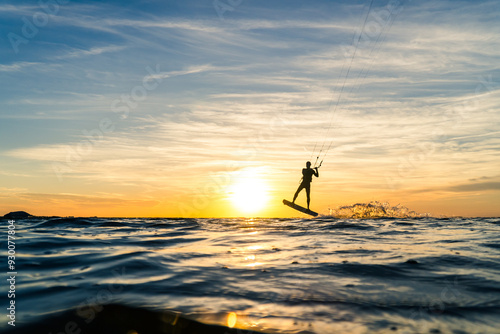 Silhouette of Kitesurfer performing jump in sunset conditions at the baltic sea
