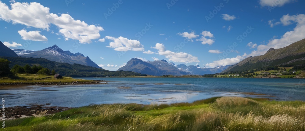 A crystalline body of water nestled amongst mountains under a vast, blue sky dotted with wispy clouds Verdant grass blankets the landscape in the foreground A crystalline body of water nestled amongst mountains under a vast, blue sky dotted with wispy clouds Verdant grass blankets the landscape in the foreground