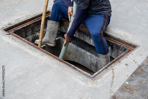 Foto A man is carrying a suction hose from the Waste Water Treatment Plant to the suction truck