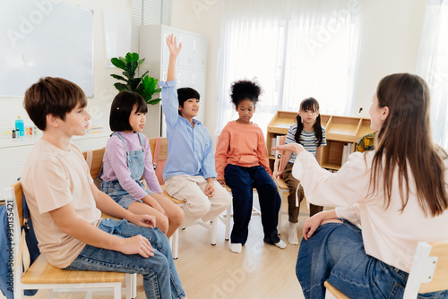 Multicultural primary school children participate in engaging group lesson. Teacher facilitates active learning through circular seating arrangement, encouraging student involvement and communication