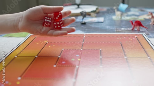 The hand throws red dices on the playing field. Gaming moments in dynamics. Luck and excitement. Board games strategy. Slow motion.