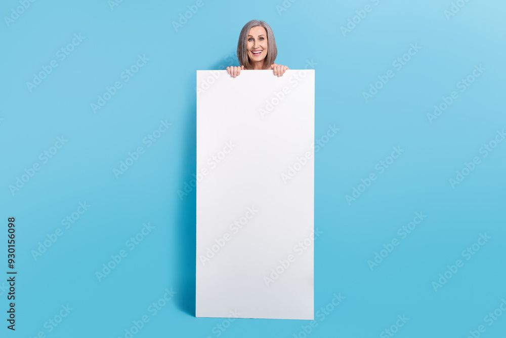 Full size photo of cheerful funny grandmother dressed pink pullover jeans hold smartphone panel ui isolated on blue color background Full size photo of cheerful funny grandmother dressed pink pullover jeans hold smartphone panel ui isolated on blue color background
