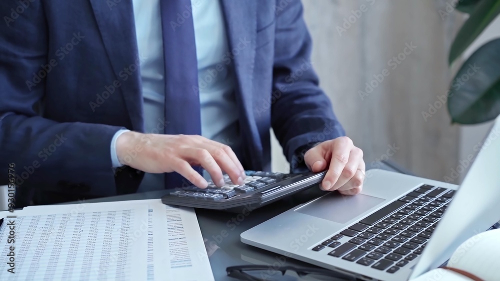 Businessman analyzing financial data on laptop and calculator. Close-up of a professional auditor working on financial reports. Business concept Businessman analyzing financial data on laptop and calculator. Close-up of a professional auditor working on financial reports. Business concept