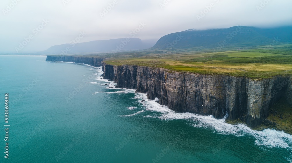 Obraz premium Aerial view of dramatic cliffs along a rugged coastline with crashing waves.