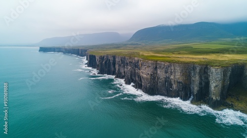 Aerial view of dramatic cliffs along a rugged coastline with crashing waves.