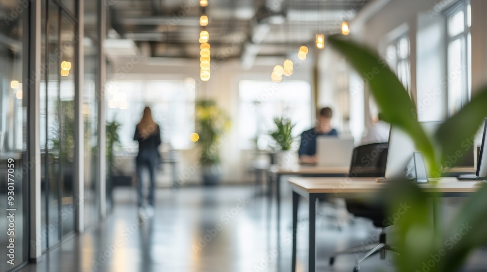 Obraz premium Two professionals are engaged in work at desks in a contemporary office filled with greenery, illuminated by natural light