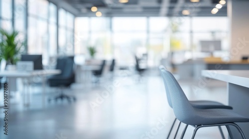 Bright and spacious office setting with empty chairs, large windows allowing natural light, and greenery, designed for productivity and collaboration