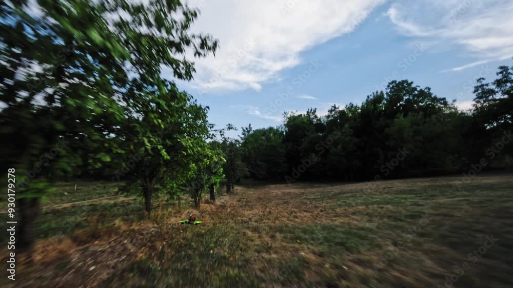 The camera chase follows an fpv racing drone performing manvra stunts while flying over a green field with a rural road under a blue sky with a first person view of the clouds. Aerial view. The camera chase follows an fpv racing drone performing manvra stunts while flying over a green field with a rural road under a blue sky with a first person view of the clouds. Aerial view.