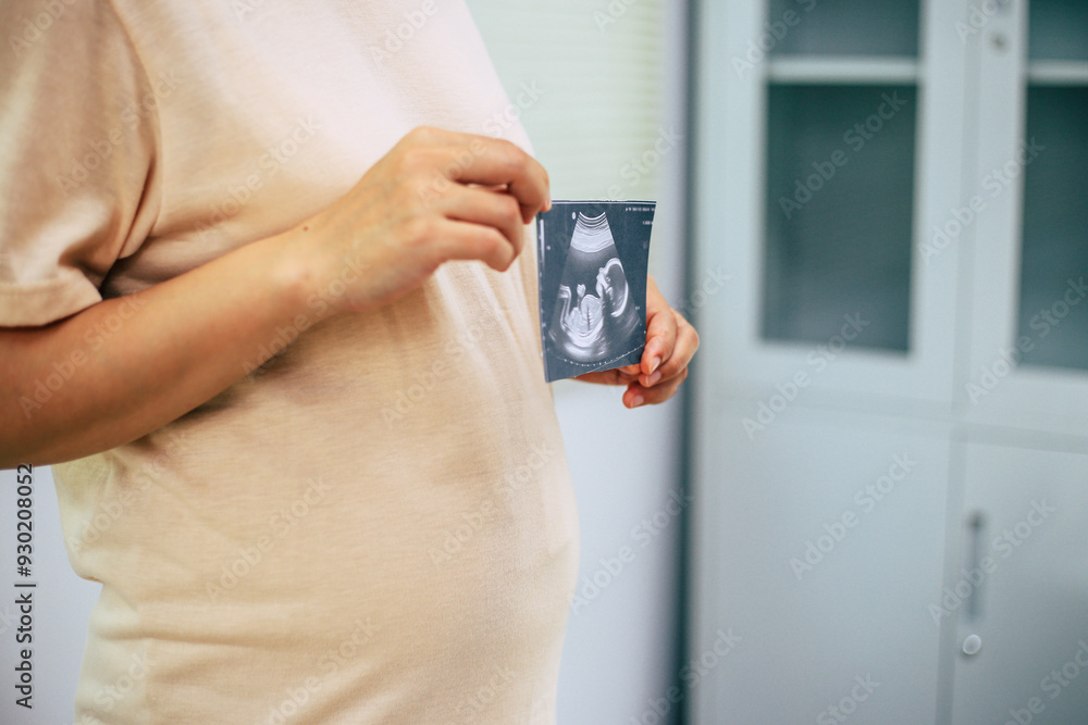 Detail of pregnant woman wearing white clothing and holding her belly with both hands. Detail of pregnant woman wearing white clothing and holding her belly with both hands.