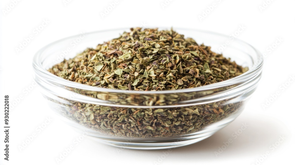 A glass bowl filled with dried oregano seasoning, isolated on a white background, with a focus on the finely crushed leaves and subtle color variations. A glass bowl filled with dried oregano seasoning, isolated on a white background, with a focus on the finely crushed leaves and subtle color variations.