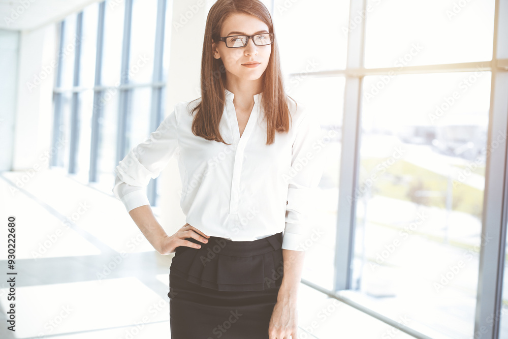 Beautiful female specialist with dark hair standing in sunny office and smiling charmingly. Working on design, data analysis, plan strategy Beautiful female specialist with dark hair standing in sunny office and smiling charmingly. Working on design, data analysis, plan strategy