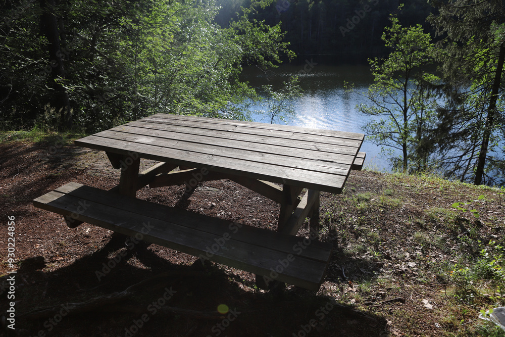 Wooden picnic table by the lake. Empty bench in forest near lake in Norway. Wooden picnic table by the lake. Empty bench in forest near lake in Norway.