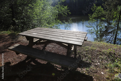 Wooden picnic table by the lake. Empty bench in forest near lake in Norway.