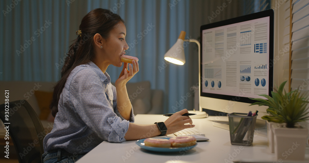 © ChayTee - Asia people young girl work busy at home office sit on desk crave sweet junk fast food eat bite donut at night. Workforce issue bad habit stress relief by fat diet break time late dinner in hard job.