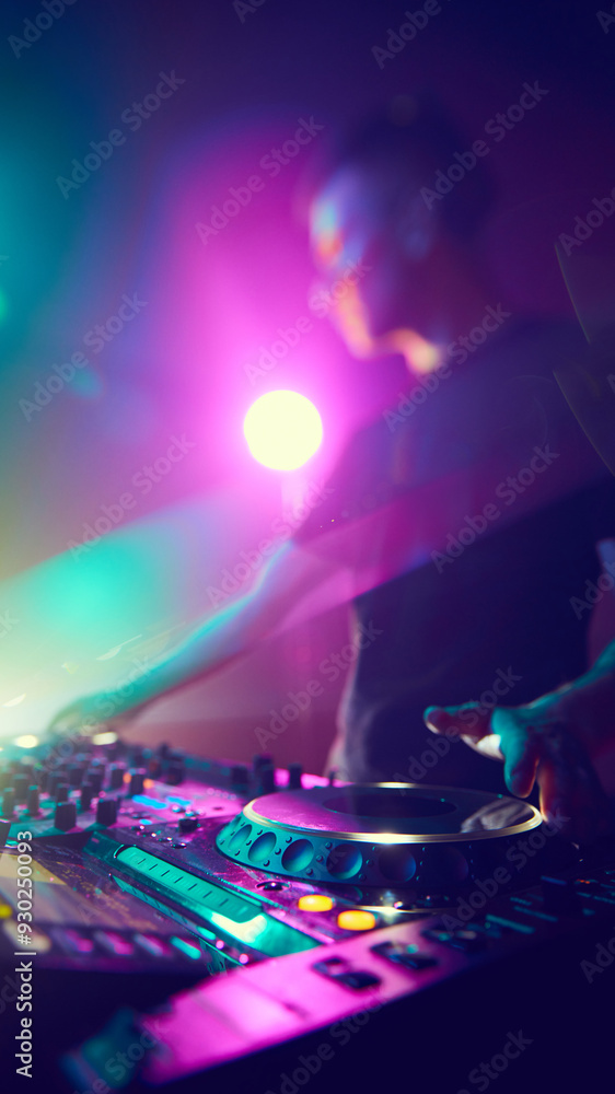 Obraz premium DJ, immersed in vibrant hues, crafts musical journey, his hands moving effortlessly over controls as lights dance around him. Concept of modern music and technology, party, disco, nightlife.