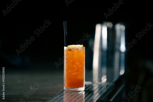 close up Cocktail with orange on bar counter in restaurant pub Orange drink with juice Fresh prepared alcoholic cooler photo