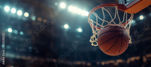 A basketball entering the hoop during a game in a brightly lit arena, focus on action and sportsmanship. copy space photo