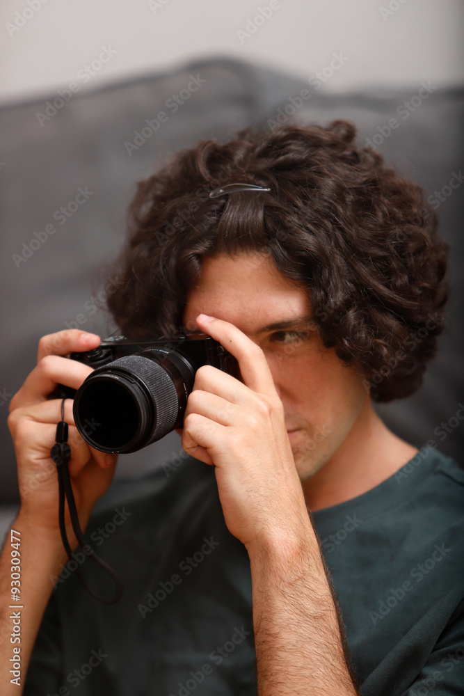cool young man looking through the viewfinder of his camera at home cool young man looking through the viewfinder of his camera at home