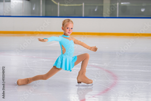 Full length portrait of little girl doing figure skating on indoor rink during performance