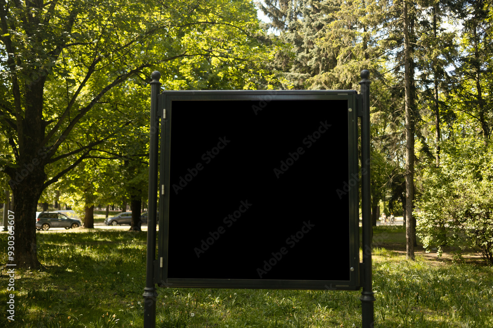 Mockup of the blank black street city outdoor advertising square billboard in black frame at park entrance. High quality photo