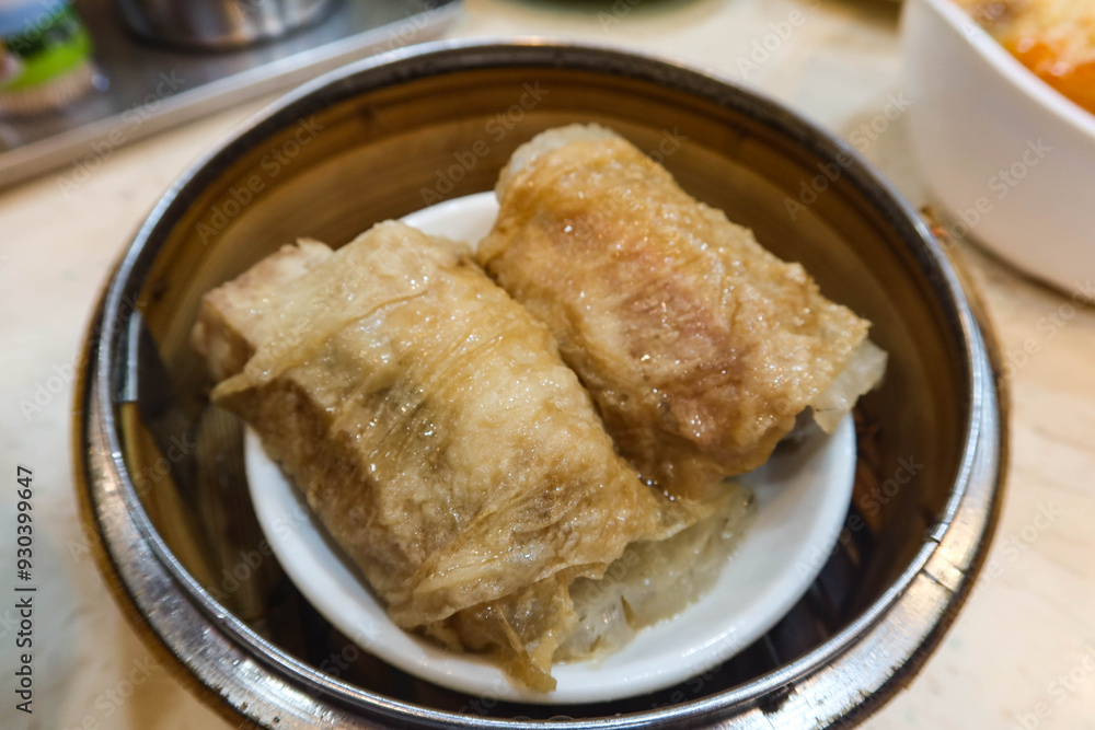 close up of Chinese Cantonese Dim Sum Steamed Chicken bean curd skin Roll with shrimp fish skin in a bamboo steamer container ordered in close up of Chinese Cantonese Dim Sum Steamed Chicken bean curd skin Roll with shrimp fish skin in a bamboo steamer container ordered in