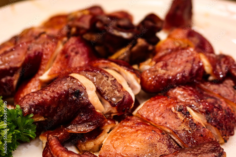 close up of grilled soy sauce chicken on a white plate with crispy skin close up of grilled soy sauce chicken on a white plate with crispy skin