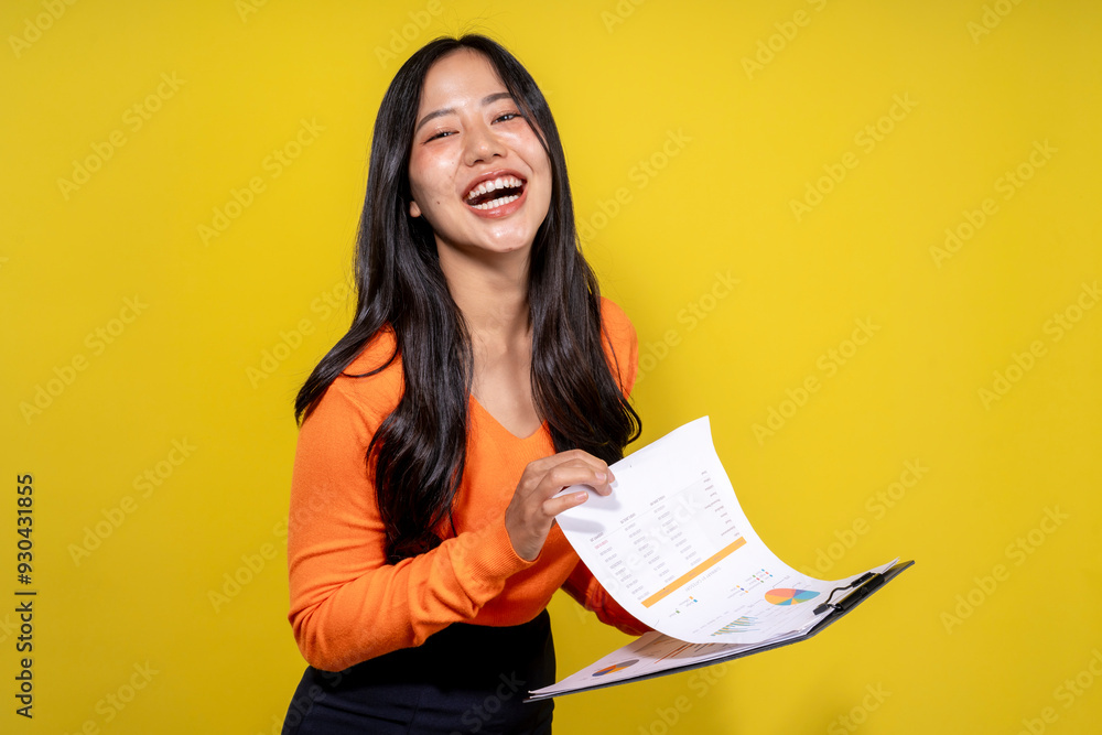 Fototapeta premium A woman in an orange shirt is holding a clipboard with a smile on her face