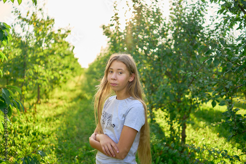 a portrait of a teenage girl with long blond hair in a sunlit garden