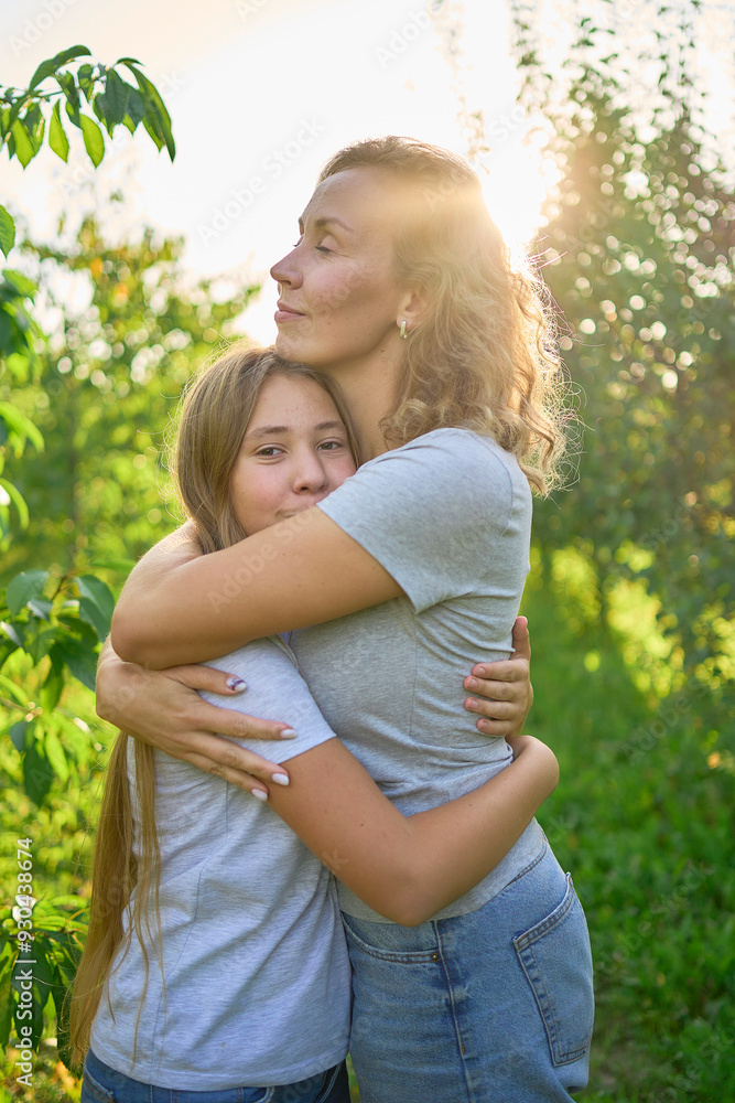 mother and teenage girls with long blond hair spend time together in the sunlit park mother and teenage girls with long blond hair spend time together in the sunlit park