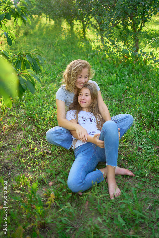 Fototapeta premium mother and teenage girls with long blond hair spend time together in the sunlit park