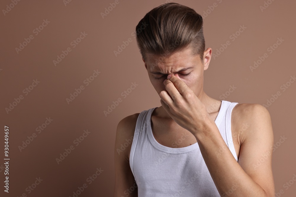 Young man suffering from sinusitis on light brown background, space for text Young man suffering from sinusitis on light brown background, space for text
