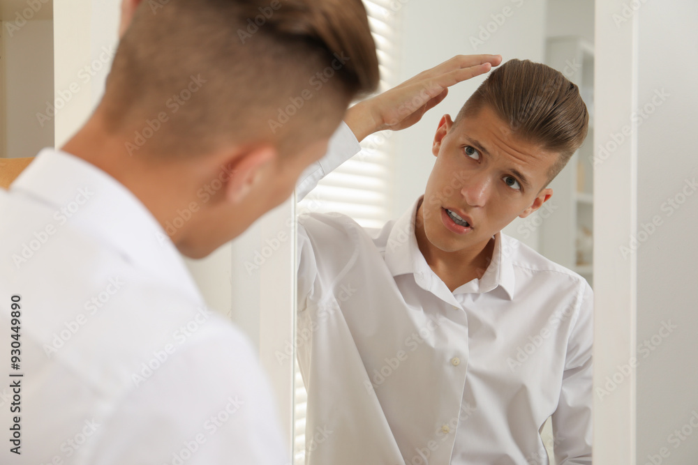 Handsome man in shirt looking at mirror indoors Handsome man in shirt looking at mirror indoors