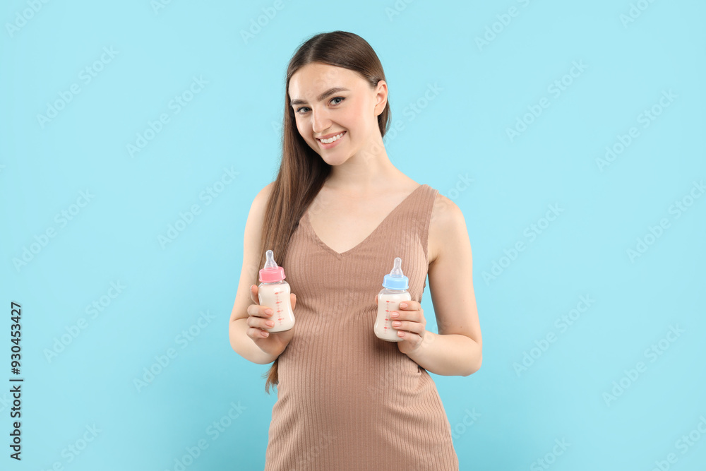 Expecting twins. Pregnant woman holding two bottles with milk on light blue background Expecting twins. Pregnant woman holding two bottles with milk on light blue background