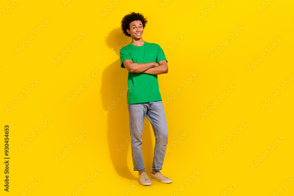 Fototapeta premium Full length photo of attractive funny guy wear green t-shirt arms crossed emtpy space isolated yellow color background