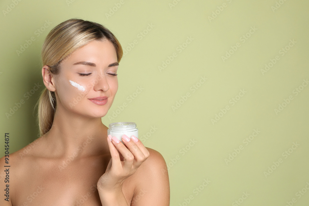 Beautiful woman with jar of facial cream against green background, space for text Beautiful woman with jar of facial cream against green background, space for text