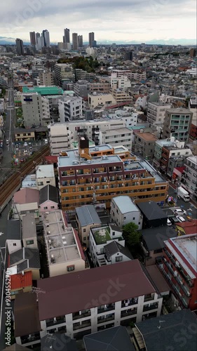 Aerial footage captures a forward drone drift over a Tokyo suburb. The scene highlights densely packed residential homes,