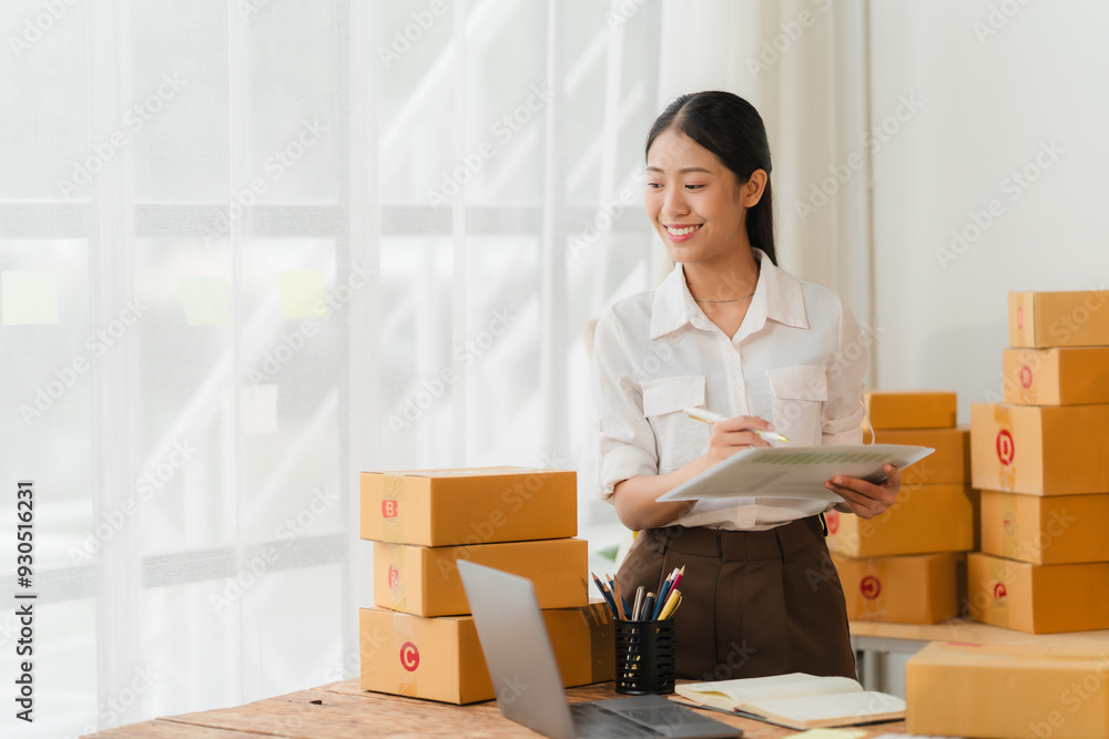 Smiling Entrepreneur: A young businesswoman in a white shirt and brown skirt stands in her home office, surrounded by stacks of cardboard boxes, a laptop, and a clipboard. She is smiling and looking a Smiling Entrepreneur: A young businesswoman in a white shirt and brown skirt stands in her home office, surrounded by stacks of cardboard boxes, a laptop, and a clipboard. She is smiling and looking a