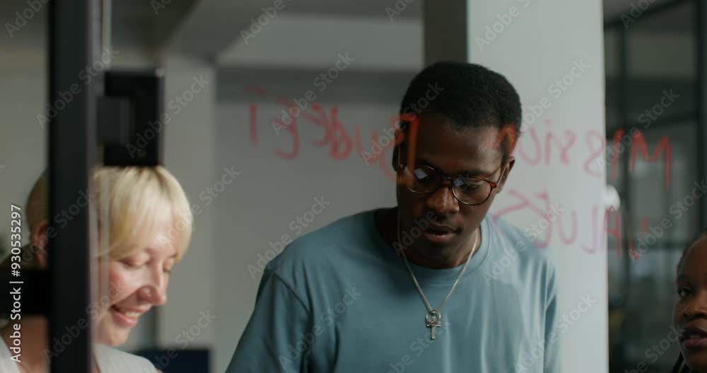 A meeting in a modern office. A group of young people are talking and writing on a glass board planning a business. They're smiling. A meeting in a modern office. A group of young people are talking and writing on a glass board planning a business. They're smiling.