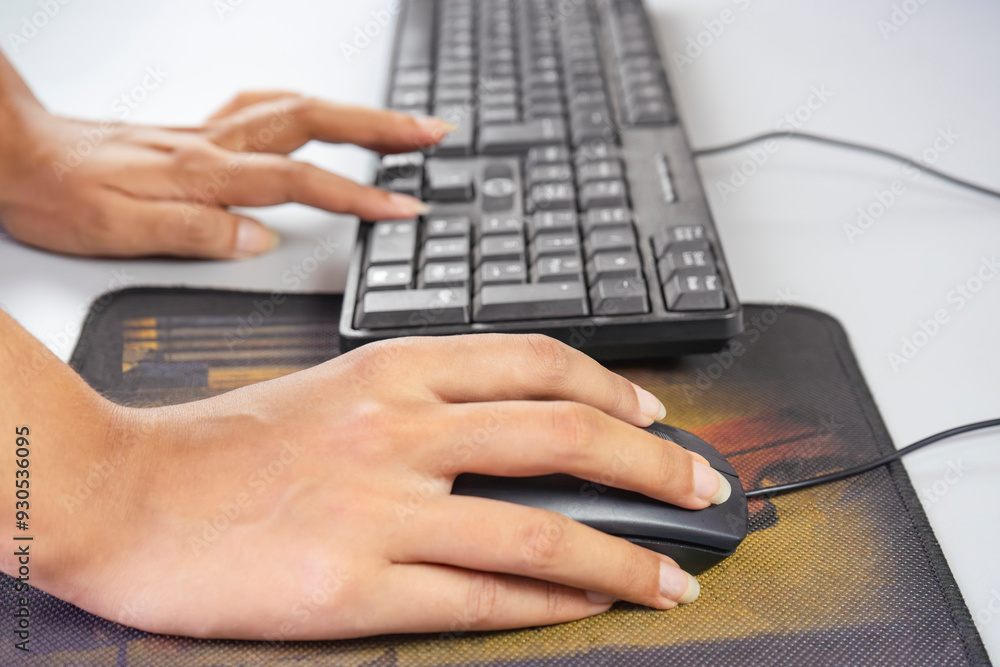 Hands working on a computer with notepad to write with keyboard and mouse Hands working on a computer with notepad to write with keyboard and mouse