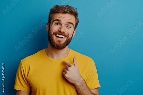 Excited Bearded Man in Yellow Shirt Pointing at Copy Space on Blue Background