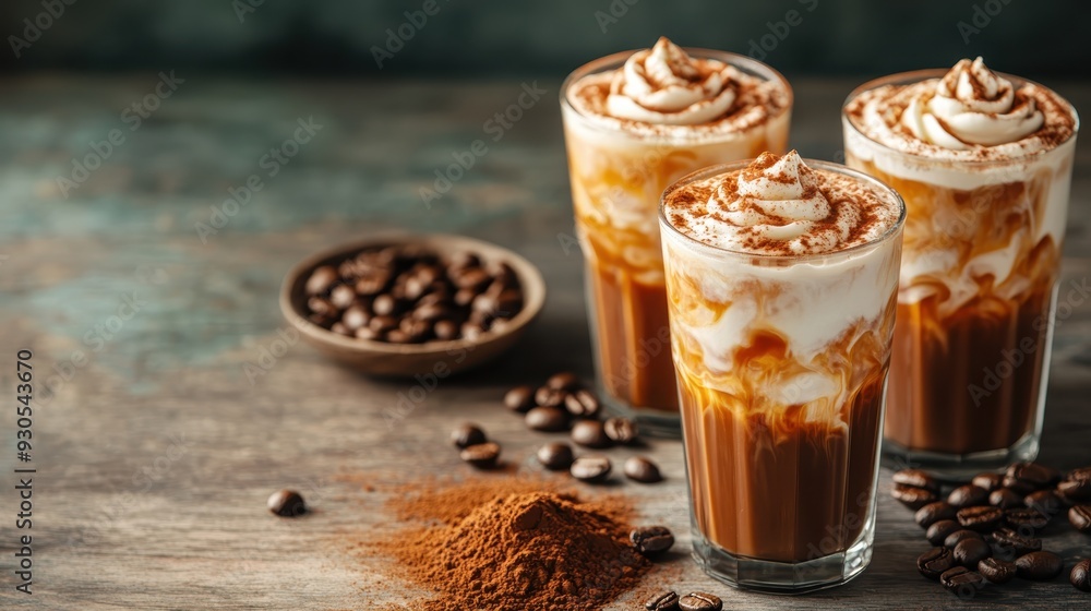 Three glasses of creamy iced coffee topped with whipped cream and dusted with cocoa powder are beautifully presented on a rustic table with coffee beans and cocoa powder. Three glasses of creamy iced coffee topped with whipped cream and dusted with cocoa powder are beautifully presented on a rustic table with coffee beans and cocoa powder.