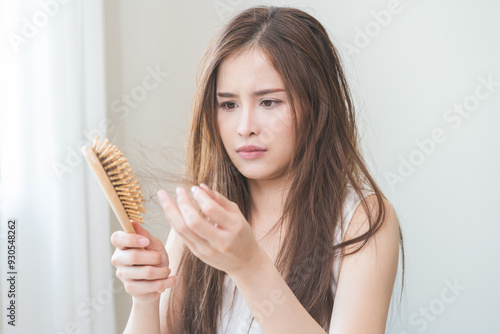 Damaged hair, amazed asian young woman, girl hand holding brush comb, hairbrush with fall hair from scalp after brushing, face worry about balding. Health care, beauty treatment, hair loss problem.