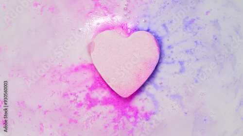 Pastel colored heart shape bath bomb dissolves in water