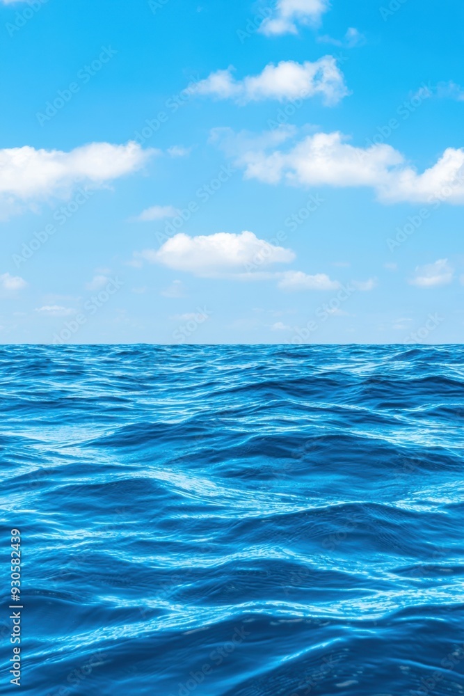 Fototapeta premium Tranquil ocean view featuring vibrant blue water and fluffy clouds against a clear sky, ideal for relaxation and nature themes.